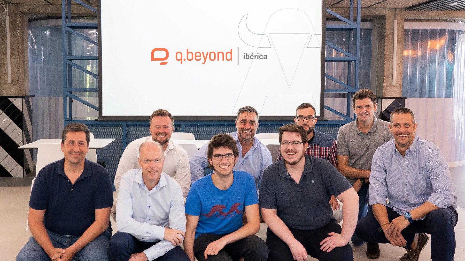 Foto grupal de nueve personas sonriendo frente al logotipo de q.beyond ibérica