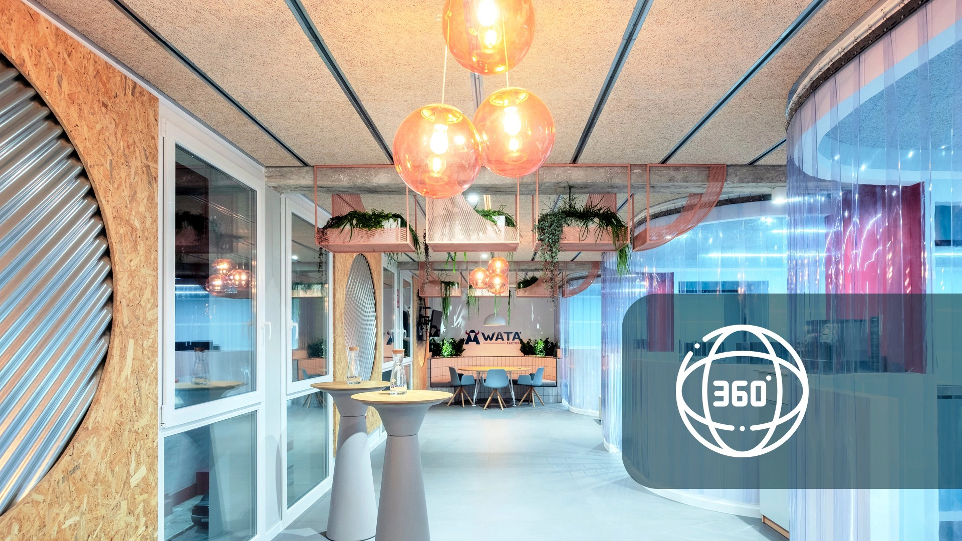 Espacio de oficina moderno con lámparas de techo naranjas, plantas y particiones de vidrio