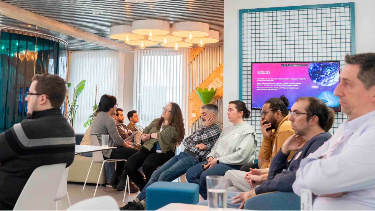 Teammeeting im WATA Factory-Büro mit Präsentation am Bildschirm, die Vorteile in lila und blauem Design zeigt