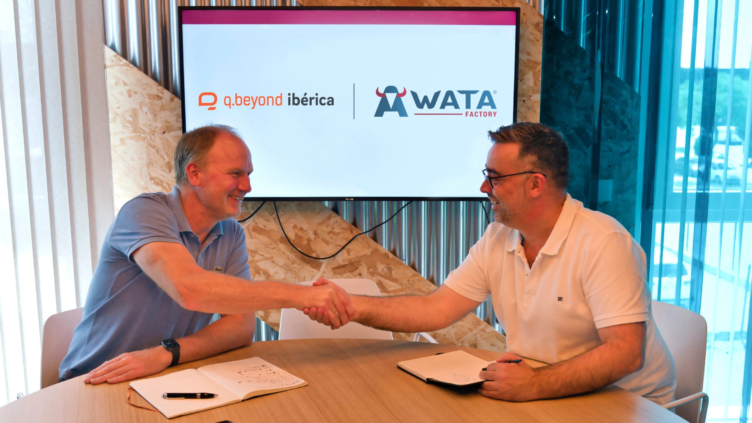 Vertreter von q.beyond ibérica und WATA Factory beim Händeschütteln während eines Treffens