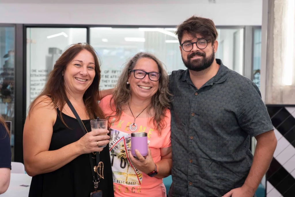 Two women and a man from WATA Factory smiling while having coffee during the All Hands break.