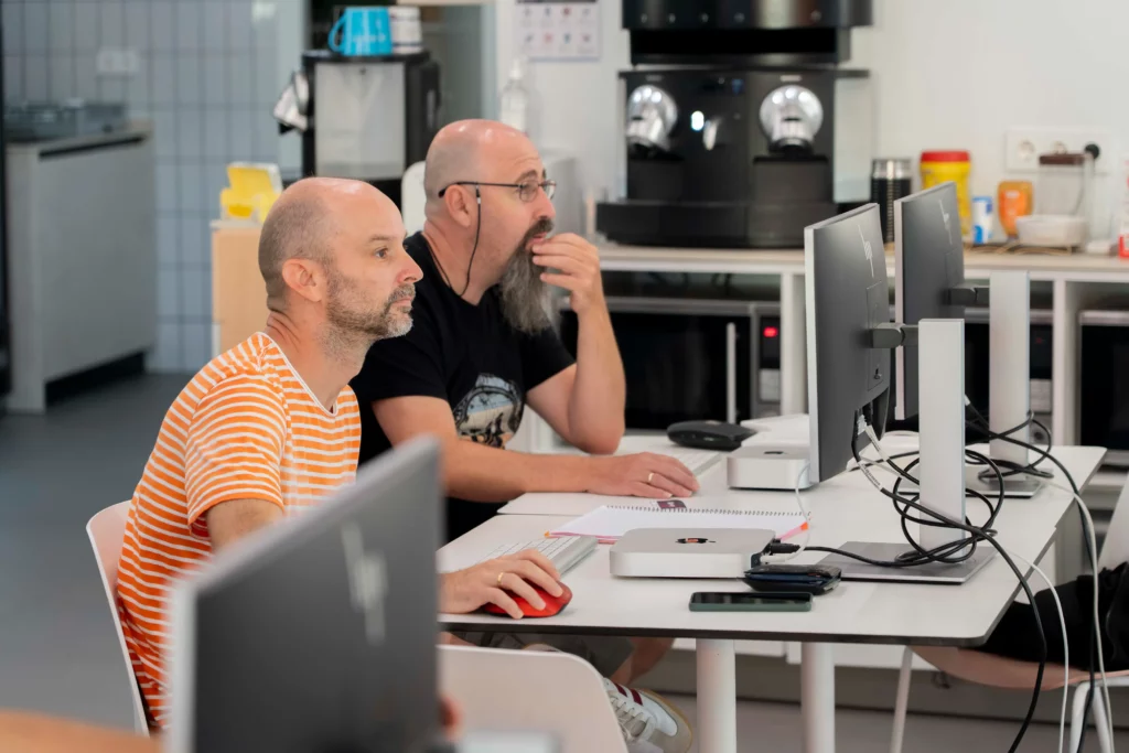 Two WATA Factory employees focused on the stage during the Kubernetes explanations.