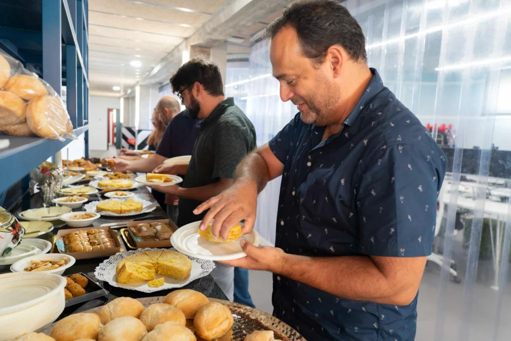 Lunch buffet at WATA Factory with bread, tortillas, empanadas, and cheese, with colleagues serving food.