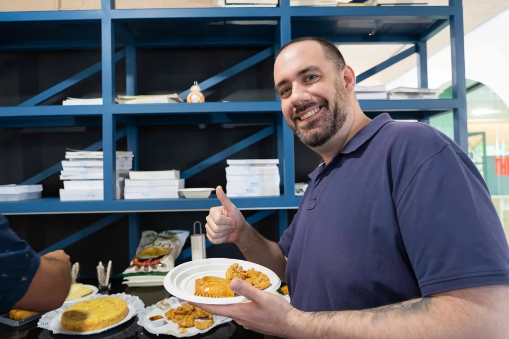 Ein weiterer Mitarbeiter von WATA Factory zeigt stolz seinen Teller mit Essen vom All Hands-Buffet.
