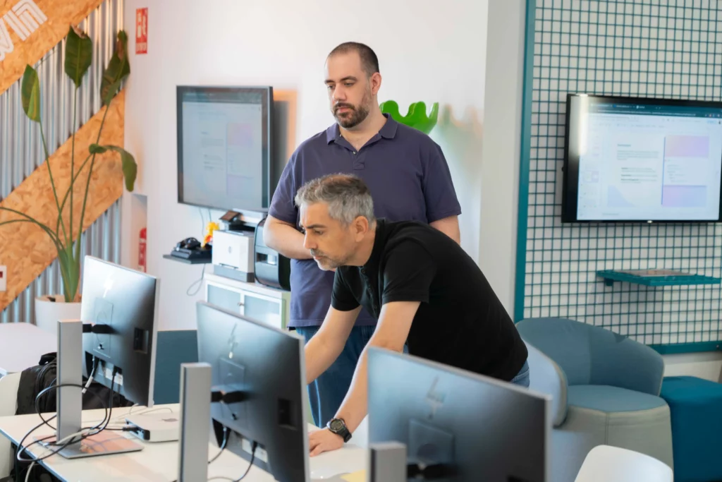 Two WATA Factory employees focused on a screen during the DevOps and Kubernetes workshop.