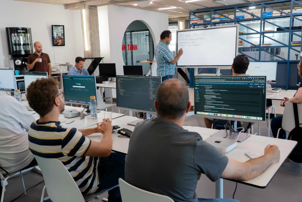 Pedro G. explaining the hands-on Kubernetes workshop while employees listen attentively.