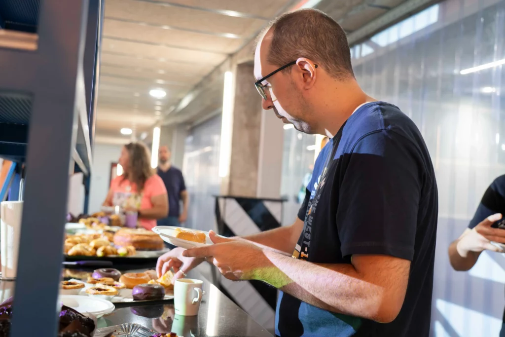 Empleado de WATA Factory sirviéndose bollería en el desayuno previo al taller de Kubernetes.