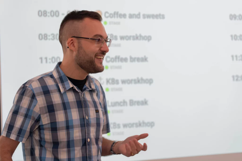Eliezer L., director of WATA Factory, smiling while presenting the agenda of the All Hands on Kubernetes and DevOps.