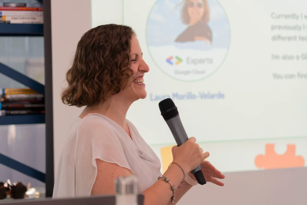 Laura Morillo-Velarde smiling with a microphone during her DevOps and Kubernetes presentation at WATA Factory.