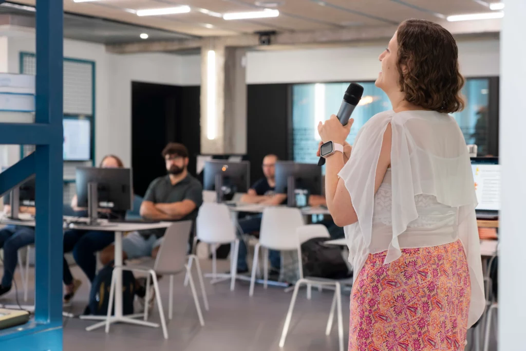 Rear view of Laura Morillo-Velarde with WATA Factory employees working on laptops during the Kubernetes workshop.