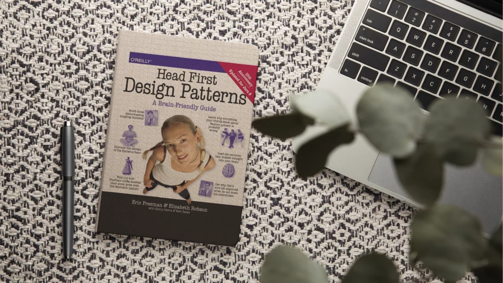 Head First Design Patterns book cover next to a laptop – top developer book 2026 on software design patterns.