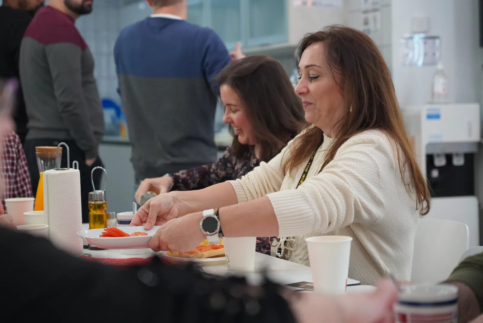 Two colleagues preparing mollete toast with ham and olive oil during the All Hands breakfast.