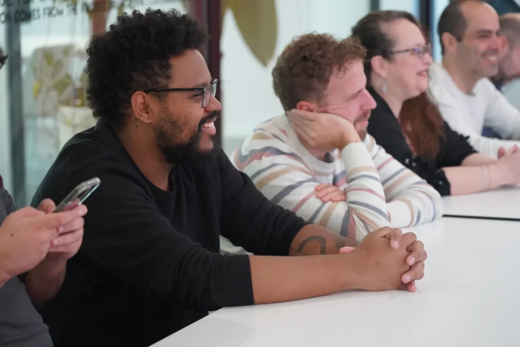 A colleague smiling while listening to the welcome speech by Germán T., CEO of WATA Factory.