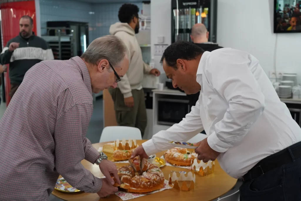 Two colleagues choosing slices of Three Kings cake during the Christmas breakfast.