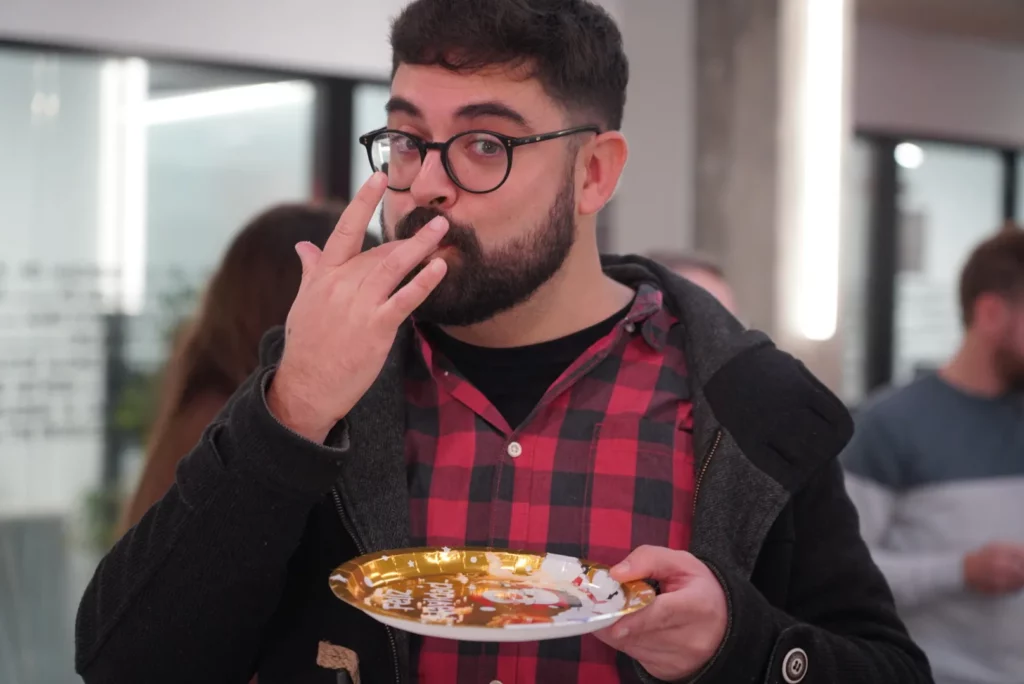 A colleague licking his fingers in approval after tasting the Three Kings cake.