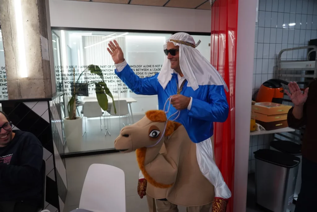 Pedro G. dressed as a Bedouin riding an inflatable camel during the All Hands.