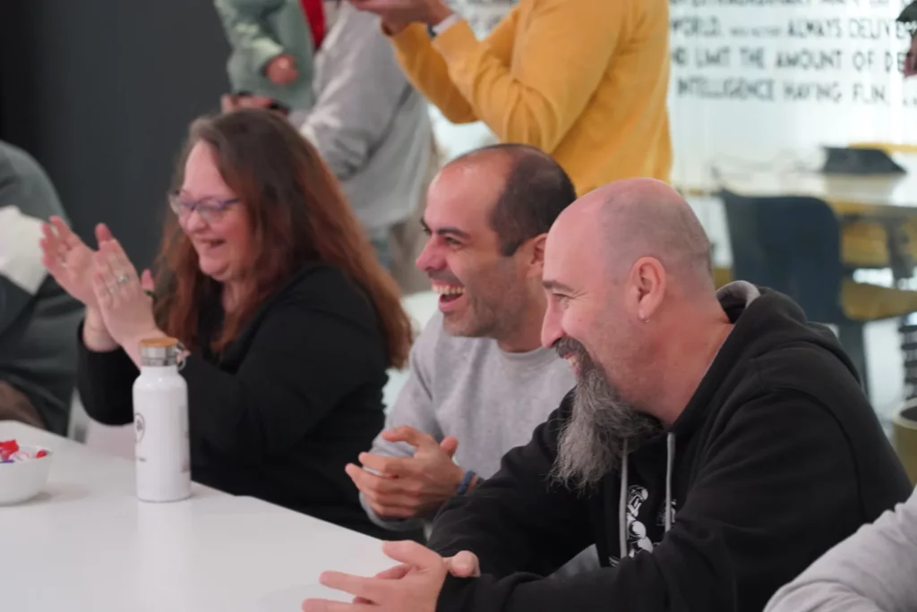 Colleagues laughing and applauding loudly at the surprise costumes.