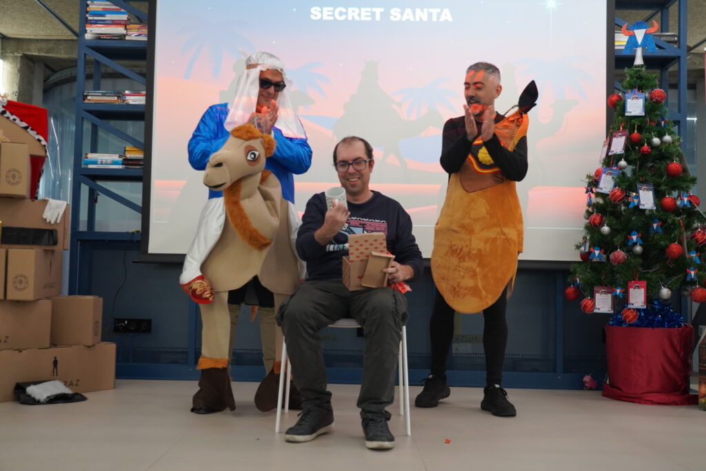 A colleague opening his Secret Santa gift and discovering a mug, a classic All Hands tradition.